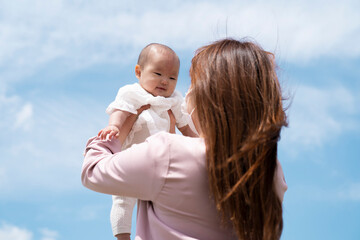 Fototapeta premium 赤ちゃんを高い高いする女性（マスク） 
