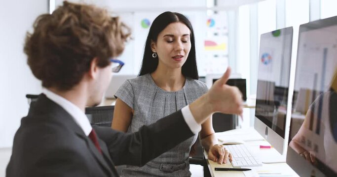 Smart executive businesswoman sitting in office with hipster look businessman colleague, discuss explain concept and idea in front of desktop computer with happy and intimate. Teamwork friends concept