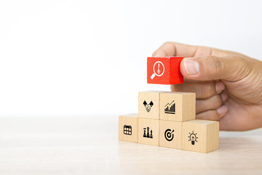 Hand choose cube wooden block stack with the key on business strategy icon with graph and arrow bullseye of strategic plan and marketing organization management for success and growth concepts.