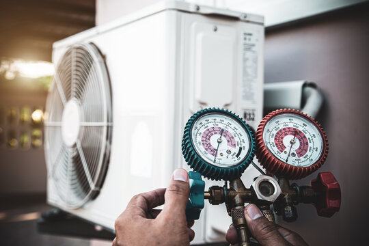 Close-up engineer using measuring manifold gauge for filling industrial air conditioner after cleaner and checking for maintenance outdoor air compressor unit.