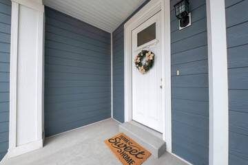White front door of a house with wreath below the window panel