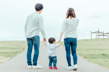 手を繋いで歩く家族（後ろ姿）
