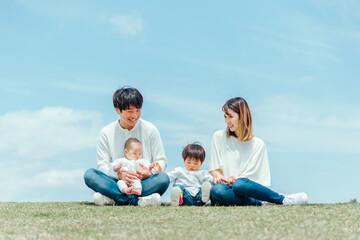 空と芝生に座る家族・ファミリー（4人）
