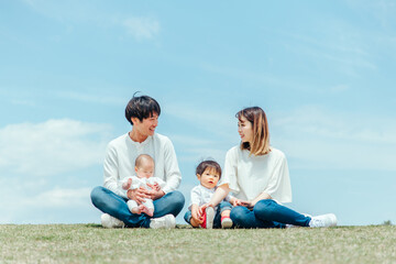 空と芝生に座る家族・ファミリー（4人）
