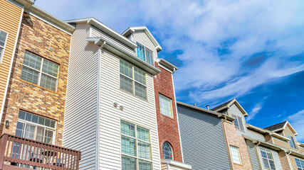 Obraz premium Pano Townhouses on a sunny day setting with balconies overlooking scenic skyscape