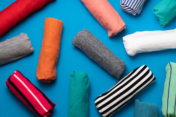 close up of rolled colorful t shirt clothes on blue table background