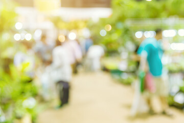 Blur Green plant tree and agriculture event in large exhibition center hall with people walking for shopping houseplant for background.