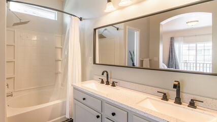 Fototapeta na wymiar Pano Open white masters bathroom with double vanity sink and bathtub shower with white curtain