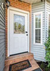 Vertical Front door exterior with bricks and vinyl siding wall