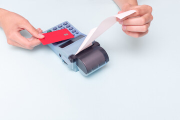 Payment for purchases by credit card. Close-up of a hand holding a bank card and a hand holding a check, receipt on a cash register on a blue background. Business concept, retail, online sale