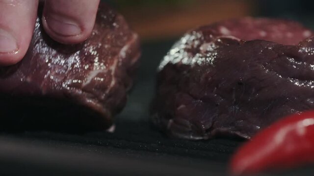 Cooking meat on the grill. The chef puts juicy fresh beef filet mignon steaks on a hot frying pan with his hands. Fried meat in the restaurant kitchen. Cooking in the kitchen