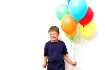 Happy eight year old boy with an armful of bright colorfull balloons celebrates birthday.