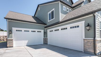 Pano Exterior of a house with concrete driveway and two closed white garage doors with windows - Powered by Adobe