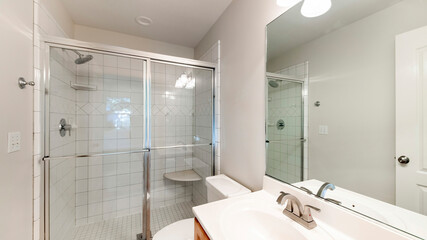 Pano Interior of a bathroom with wooden vanity sink with tile counter and shower stall with glass