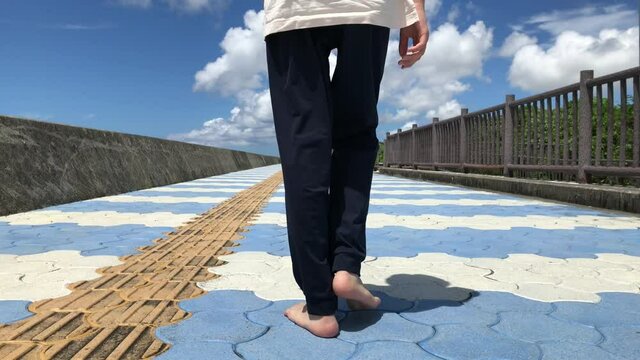 素足で美しい海岸沿いのストリートを走る少年の後ろ姿