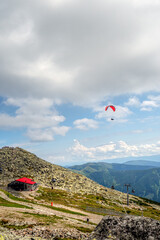 view of a mountain top shooted from Chopok, famous Low Tatra mountain with its beautiful scenery of summer surroundings with paraglider over Kamenna chalet