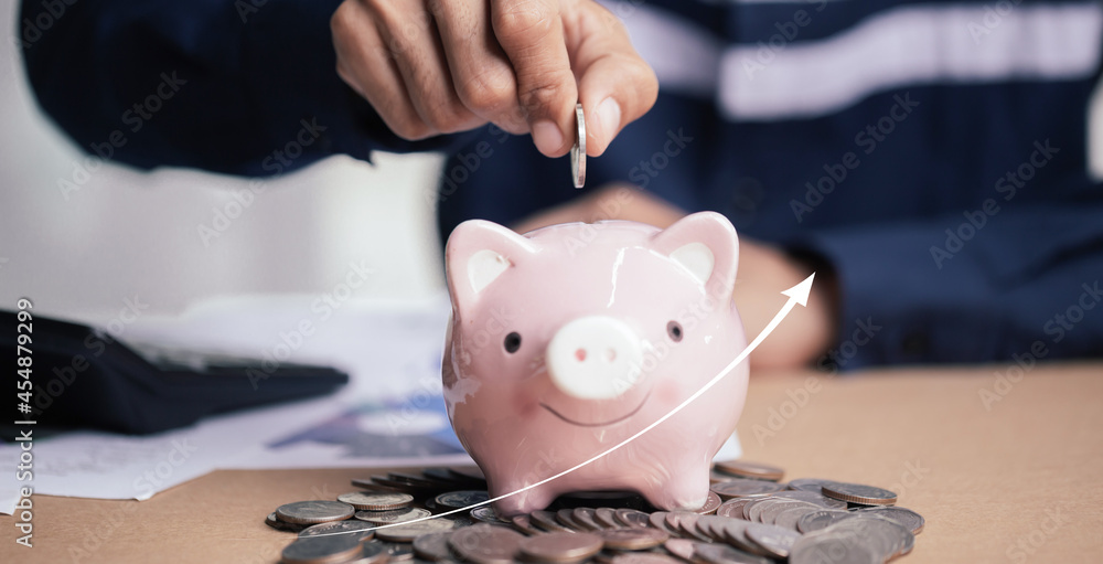 Wall mural man hand putting money coin into piggy for saving money wealth and financial concept.