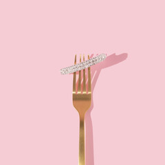 Creative  layout golden fork and  hair pin with gemstones on pastel pink background. Luxury fashion...