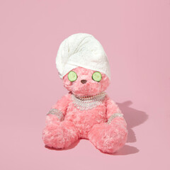 Creative layout with pink teddy bear with towel turban, cucumber slices and luxury jewelry on...