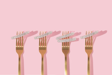 Creative  pattern or frame with golden fork and  hair pin with gemstones on pastel pink background....