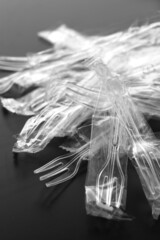 黒い背景の中のプラスチック製のスプーンやフォーク