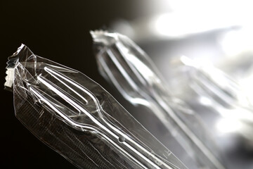 黒い背景の中のプラスチック製のスプーンやフォーク