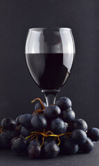 Wine glass and black grapes. Dark background and copy space.