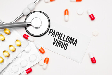 Stethoscope, pills and notebook with Papilloma virus word on medical desk.