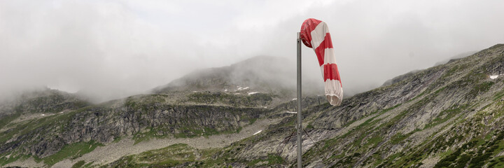 Panoramic image, red and white wind cone with mountains in the background