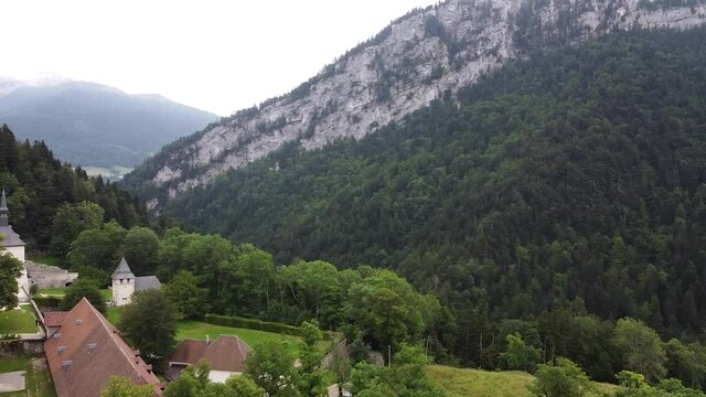 an aerial view of rocks and a casle in gorge with green trees and lawn at gloomy day