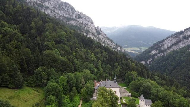 an aerial view of rocks and a casle in gorge with green trees and lawn at gloomy day