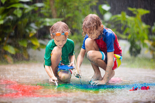 Kids playing in the rain. Chalk drawing fun.
