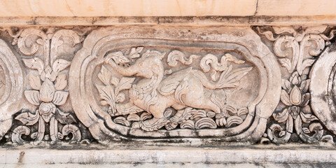 Beautiful ancient bas-relief stucco panel of a lion with elephant head, a mythological animal on wall of hor trai library in Wat Phra Singh buddhist temple, famous landmark of Chiang Mai, Thailand