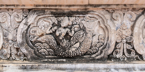 Beautiful ancient bas-relief stucco panel of a mythological half woman half fish creature on wall of hor trai library in Wat Phra Singh buddhist temple, famous landmark of Chiang Mai, Thailand