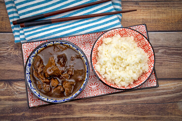 plat de morceaux de boeuf aux oignons et riz sur une table
