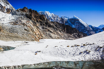 Fototapeta na wymiar Hikers Walking Up on Glacier in Nepal. Himalayas mountain range and way to Cho La Pass. Everest Base camp trek