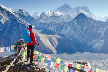 Keuken foto achterwand Mount Everest Hiker with trekking poles stands on the slope against the background of high snow-capped mountains