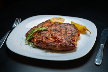 Delicious beef steak with rosemary herb on white plate. T-bone beefsteak cooked on grill for dinner...