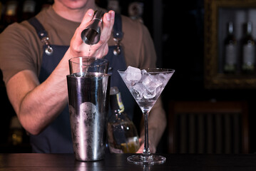 The bartender at the nightclub behind the bar making an Espresso Martini cocktail