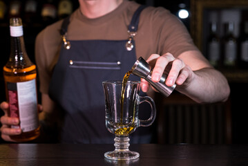 Close up hands of the bartender who make a cocktail. Irish coffee