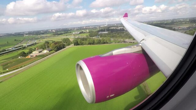 Airplane wing and engine view during landing at Amsterdam airport with view of thrust reversers