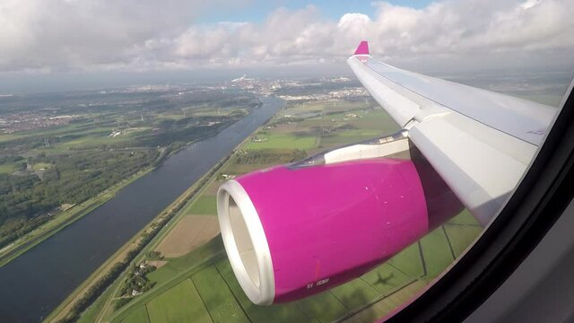Airplane wing and engine view on approach to Amsterdam airport flying over the North Sea canal