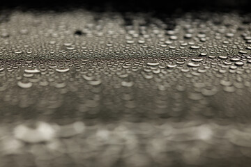 Drops on glass. Texture for designer background. Drops of water flow down the surface of the clear glass on a black background. Raindrops for overlaying on window. Concept of autumn weather.