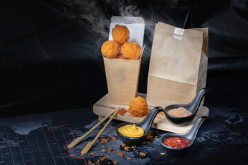 Cheese ball in paper container, hot, smoked, black background