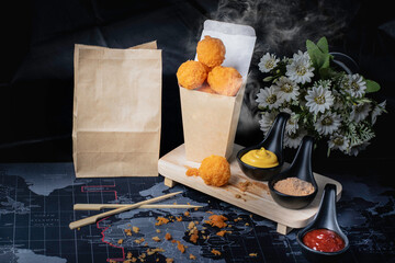 Cheese ball in paper container, hot, smoked, black background