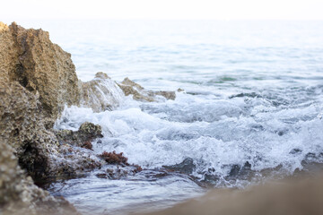 Stone in sea with wave on sunset