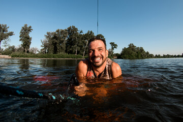 close-up of smiling adult man holding a rope in the water