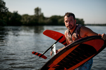 adult athletic wet man holding bright foil board in his hands