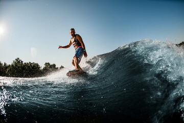 man ride down on splashing river wave on foilboard at summer day