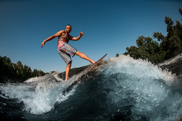 Fototapeta premium Active guy on foilboard balancing on wave against the background of blue sky.